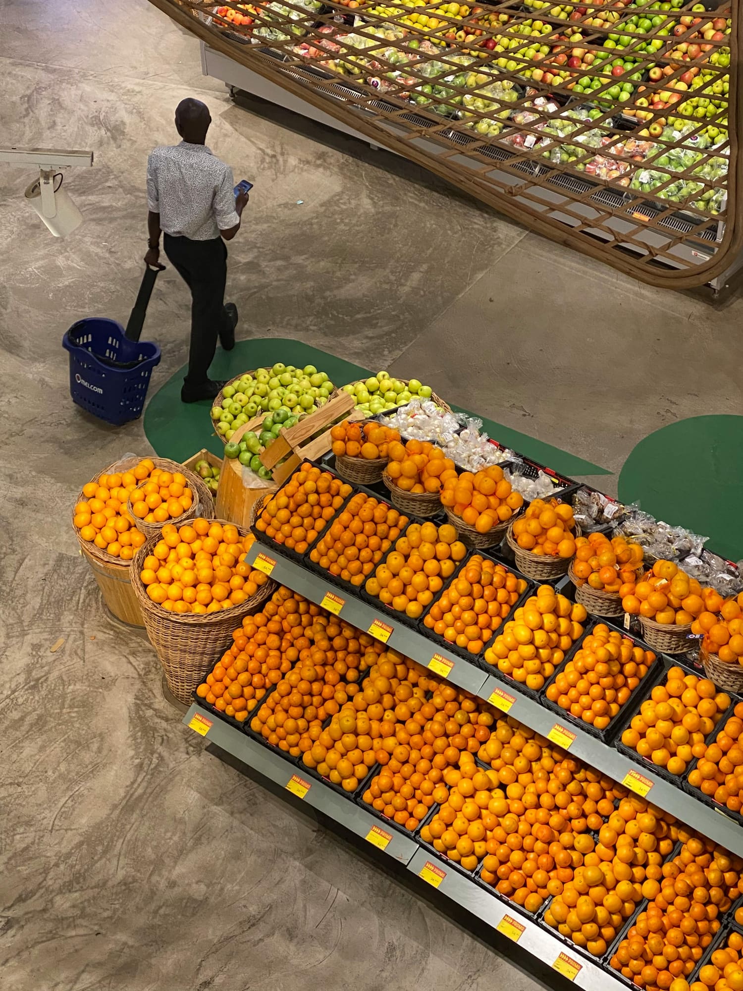 A shopper pushing a basket through a fruit display